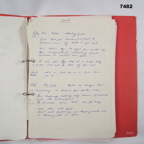 Red ring binder containing miscellaneous pages of notes both handwritten and printed in black type.