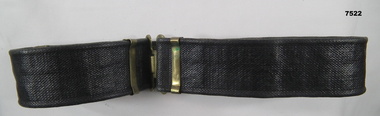 Blackened webbing belt with brass fittings and buckle.