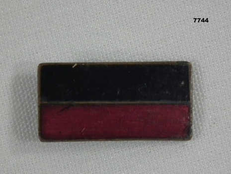 Rectangular enamelled two colour metal badge.