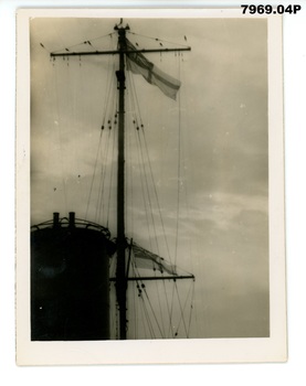 1942 08 Solomon Islands Hobart white ensign battle flag flying at main mast.jpg