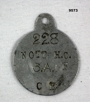 Circular metal identity disc with owner's details.