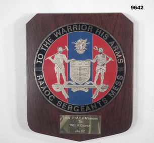 Shield shaped wooden plaque with circular shaped plate attached.