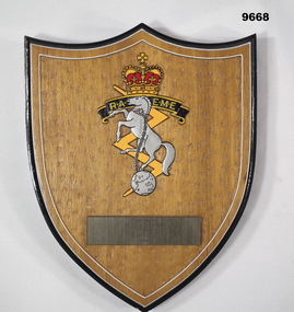 Shield shaped wooden plaque with 'RAEME' insignia and name plate.