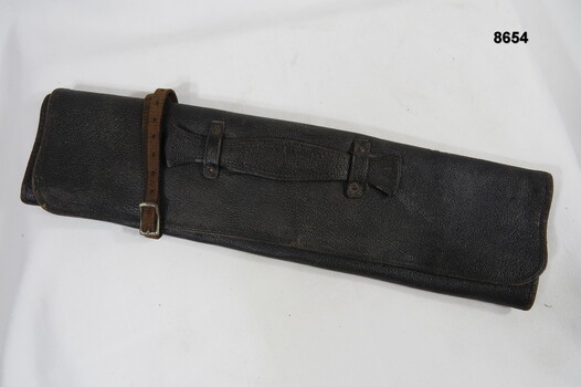 Leather document satchel with carry handle and closure strap.