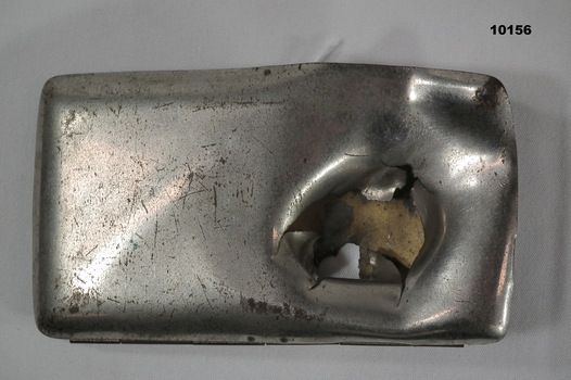 Rectangular hinged metal cigarette case with shrapnel damage.