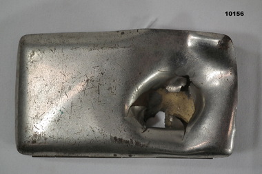 Rectangular hinged metal cigarette case with shrapnel damage.