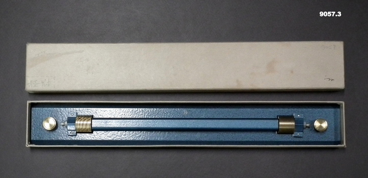 A metal rolling ruler in a cardboard box