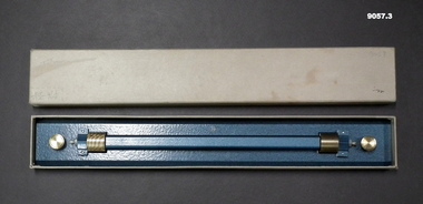 A metal rolling ruler in a cardboard box