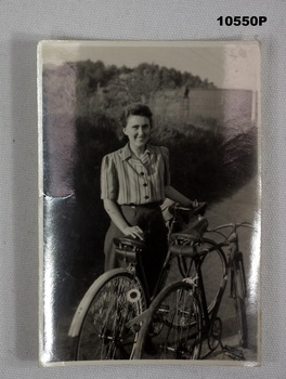 Photograph of a lady standing with bicycles.