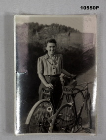 Photograph of a lady standing with bicycles.