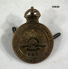 Round Bronze coloured badge - Returned from Active Service.