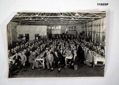 Black and white group photo of men seated at tables.