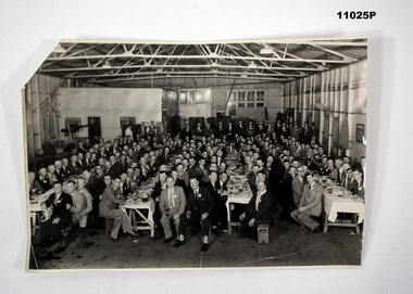 Black and white group photo of men seated at tables.