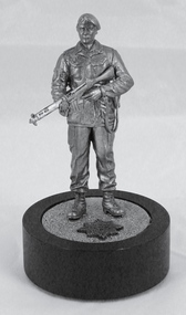 Metal miniature figurine of soldier with rifle on black cylinder base