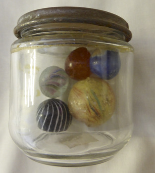 This is a glass  jar with a lid. full of varied size marbles