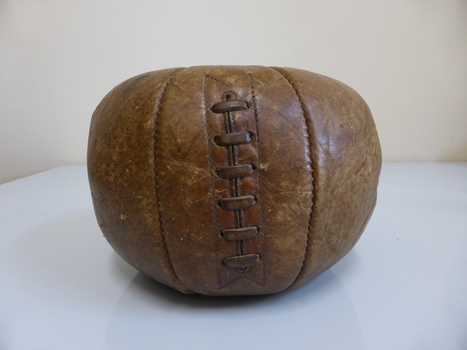 This is a brown leather medicine ball with leather lacing.