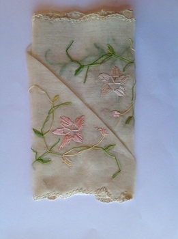 This is a white hankerchief with pink and green embroidery.