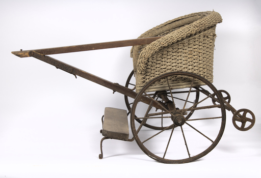 A twin push chair from the 1910's It is made mainly of cane and has two metal wheels.