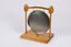 Back of dinner gong suspended by two wooden spoons attached to wooden stand. 
