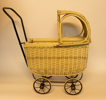 White wicker child's pram with black metal frame.