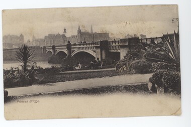Postcard in yellowing monochrome depicting a large arch bridge spanning over water with buildings in background. Two men sitting on bench in front of bridge