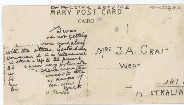 The back of a postcard, with cursive text and that is damaged in some areas.