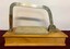 Front of cheese slicer with lowered arm. Wooden base and marble slabs.