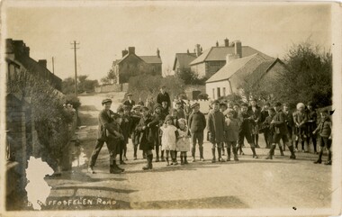 A group of children standing on a street in a Welsh village.