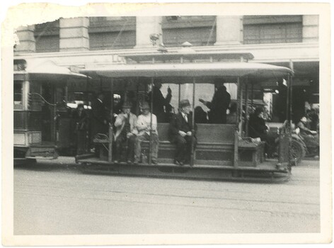 A Melbourne tramcar with men sitting on a long bench seat.