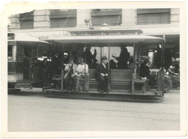 A Melbourne tramcar with men sitting on a long bench seat.