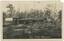An old sawmill with piles of sawn timber on the ground and background bush