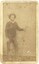 Photograph of man standing and facing the camera. He is wearing a hat and jacket and jeans. Sepia color.