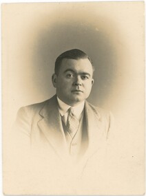 Sepia head and shoulders portrait of Ian MacLeod Murphy wearing suit and tie.