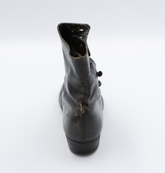 The image shows the back of the right shoe from a pair of black button-up boots.