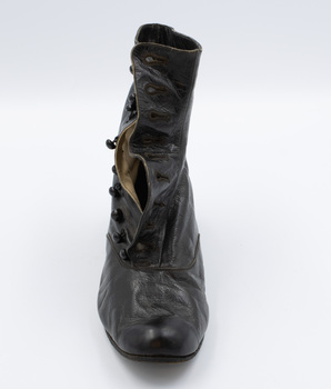 Image shows the front view of the right shoe from a pair of button-up boots with some of the inner lining revealed.