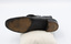 The Image shows the sole of the left shoe from a pair of black button-up boots. There is a faint engraved 3/E on the instep and a series of studs around the heel.