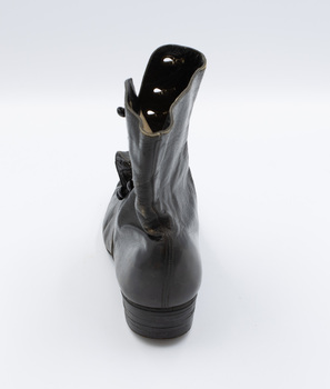 The Image shows the backside of the left shoe from a pair of black button-up boots.