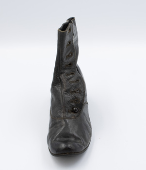 Image shows the front view of the right shoe from a pair of black button-up boots.