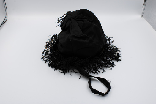 Top view of black drawstring bag with tassels and handle prominent.