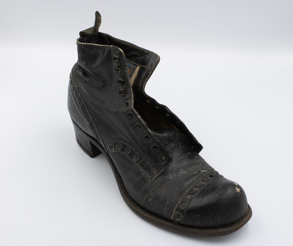A single black low-heeled left boot, angled with the toe and right side facing the camera.