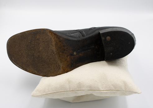 A single black low-heeled left boot, with the sole facing the camera.