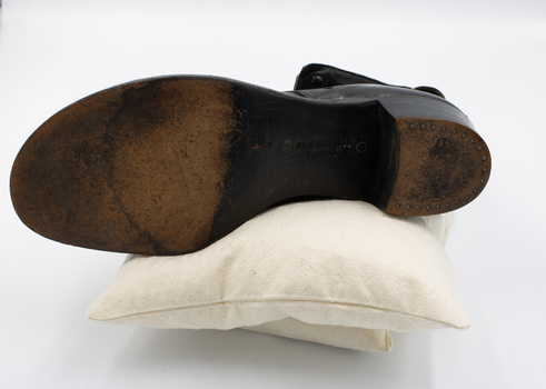 A single black low-heeled right boot, with the sole facing the camera.