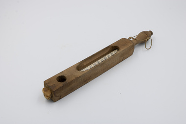 A thermometer visible through a long, rounded gap in its rectangular wooden casing.