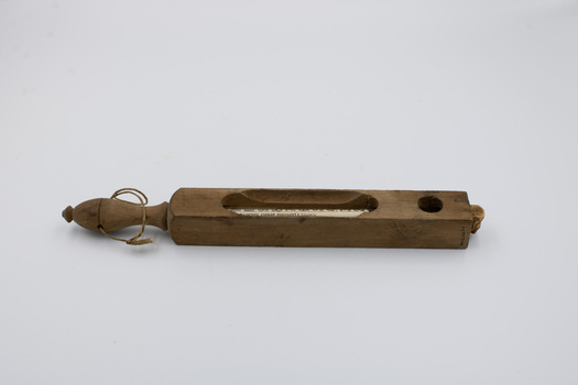 A thermometer visible through its wooden case, with a wooden handle on the end of the case.