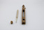 A thermometer, its empty wooden case and a cork laid out next to each other.