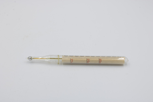 A dairy thermometer, with markings denoting appropriate temperatures for Freezing, Churning Cheese facing the camera.
