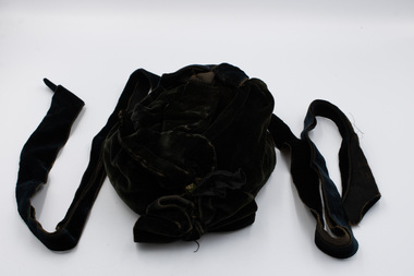 Front of black velvet hat with black velvet bow and two black ribbons for tying under the chin.
