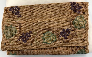 Front of handmade hessian bag with flap closed and purple, green and brown embroidery around the edge.
