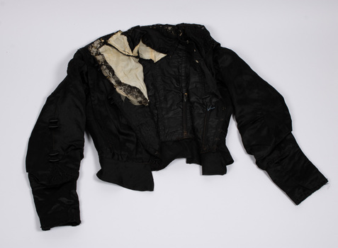 Front view of black bodice laid flat with cream inset visible