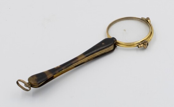 Lorgnette glasses closed. Tortoiseshell handle with brass ring at the end.